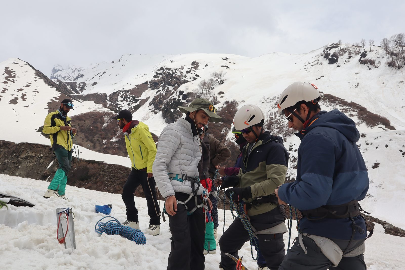 Climber in crampons and harness on snow slope